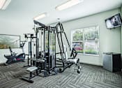 Thumbnail 18 of 31 - A gym room with a variety of equipment including a treadmill, weights, and a television.