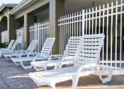 Thumbnail 11 of 15 - White pool lounge chairs on sun deck surrounded by white metal fence