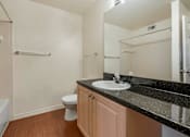 Thumbnail 21 of 24 - Bathroom with Blonde Cabinets, Black Counters and White Bathtub and Beige Shower