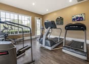 Thumbnail 7 of 24 - Fitness center cardio equipment, hardwood style flooring, and large windows for natural lighting