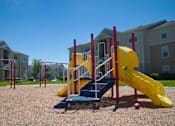 Thumbnail 4 of 24 - Blue Red and Yellow Playground on Mulch with Building Exteriors in the Background