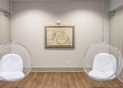 Thumbnail 55 of 197 - Two white chairs are suspended from the ceiling in a room with a framed artwork on the wall at Foxwood Apartments, North Carolina
