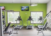 Thumbnail 84 of 197 - A gym with treadmills, elliptical machines, and a television at Foxwood Apartments, North Carolina