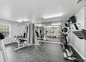 Thumbnail 3 of 29 - A spacious gym with a variety of equipment including treadmills, stationary bikes, and weight machines.