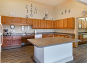 Thumbnail 22 of 24 - Clubhouse Kitchen with kitchen island, hardwood style floors, wooden cabinetry, and a white refrigerator