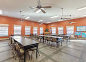 Thumbnail 23 of 24 - Clubhouse meeting room with tables, chairs, and orange walls
