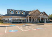 Thumbnail 26 of 27 - Clubhouse exterior with parking lot and native landscape