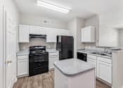 Thumbnail 4 of 27 - A kitchen with black appliances and white cabinets.