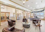 Thumbnail 14 of 27 - A large room with leather chairs and a table with a bottle on it.