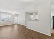Thumbnail 10 of 27 - A spacious living room with hardwood floors and white walls.