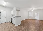 Thumbnail 7 of 27 - A kitchen with white cabinets and a wooden floor.