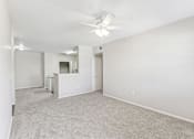 Thumbnail 11 of 27 - A spacious room with a ceiling fan and carpeted floor.