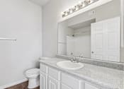 Thumbnail 8 of 27 - A white bathroom with a toilet, sink, and mirror.