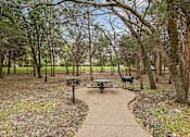 Thumbnail 28 of 33 - A picnic table sits in the middle of a park with a pathway leading to it.