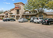 Thumbnail 33 of 33 - A parking lot with cars and a building in the background.