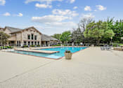 Thumbnail 9 of 33 - A large outdoor swimming pool with a building in the background.
