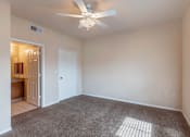 Thumbnail 5 of 33 - a bedroom with a ceiling fan and a door to a bathroom