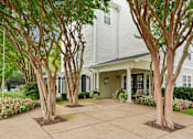 Thumbnail 16 of 29 - A house with a white exterior and a grey roof is surrounded by trees and flowers.