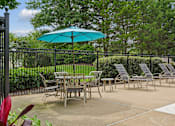 Thumbnail 12 of 29 - A patio with a table and chairs and a blue umbrella.