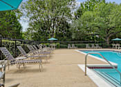Thumbnail 11 of 29 - A pool area with chairs and a table.