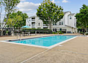 Thumbnail 6 of 29 - A swimming pool in front of a white apartment building.