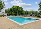 Thumbnail 7 of 29 - A swimming pool surrounded by trees and chairs.