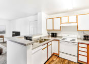 Thumbnail 13 of 25 - Model Kitchen with White Appliances, Grey Counters and White Cabinets with Wood Accents