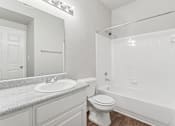 Thumbnail 13 of 27 - A white bathroom with a sink, toilet, and bathtub.