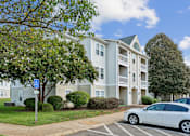 Thumbnail 26 of 29 - A white car is parked in a parking lot in front of a building.