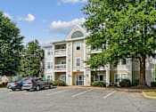Thumbnail 24 of 29 - A large apartment building with a parking lot in front.