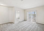 Thumbnail 11 of 24 - A spacious room with a carpeted floor and a sliding glass door.