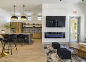 Thumbnail 30 of 39 - a living room with a large tv and a kitchen with a bar and stools