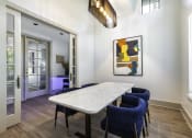 Thumbnail 35 of 39 - a dining area with a white table with blue chairs and a large colorful painting on the wall