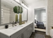 Thumbnail 16 of 39 - a bathroom with gray cabinets and a large mirror