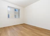 Thumbnail 25 of 44 - a bedroom with white walls and wood flooring and a window