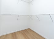 Thumbnail 28 of 44 - an empty room with white walls and wooden flooring and a white closet with shelves
