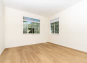 Thumbnail 35 of 44 - a bedroom with white walls and wood floors and two windows