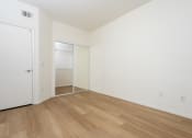 Thumbnail 39 of 44 - a bedroom with white walls and wood flooring and a closet