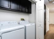 Thumbnail 42 of 44 - an empty laundry room with two washes and a dryer