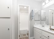Thumbnail 12 of 38 - A white bathroom with a sink, mirror, and a white cabinet.