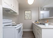 Thumbnail 3 of 38 - A small white kitchen with a fridge, stove, and sink.