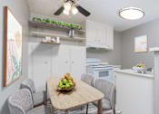 Thumbnail 2 of 38 - A kitchen with a table and chairs and a bowl of fruit on the table.