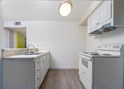 Thumbnail 17 of 38 - A small kitchen with a white stove and a green door.