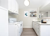 Thumbnail 10 of 38 - A white kitchen with a stove, oven, and sink.