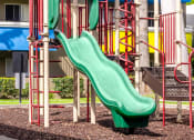 Thumbnail 5 of 13 - a playground with a green slide in front of a building