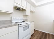 Thumbnail 7 of 17 - A white stove and oven in a kitchen with white cabinets.