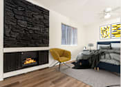 Thumbnail 12 of 17 - A modern bedroom with a stone wall and a yellow chair.