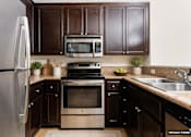 Thumbnail 1 of 27 - A kitchen with a stainless steel refrigerator, a microwave, a stove, and a sink.