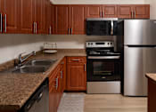 Thumbnail 16 of 36 - A kitchen with brown cabinets and a stainless steel refrigerator.