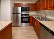 Thumbnail 25 of 36 - A kitchen with wooden cabinets and a granite counter.